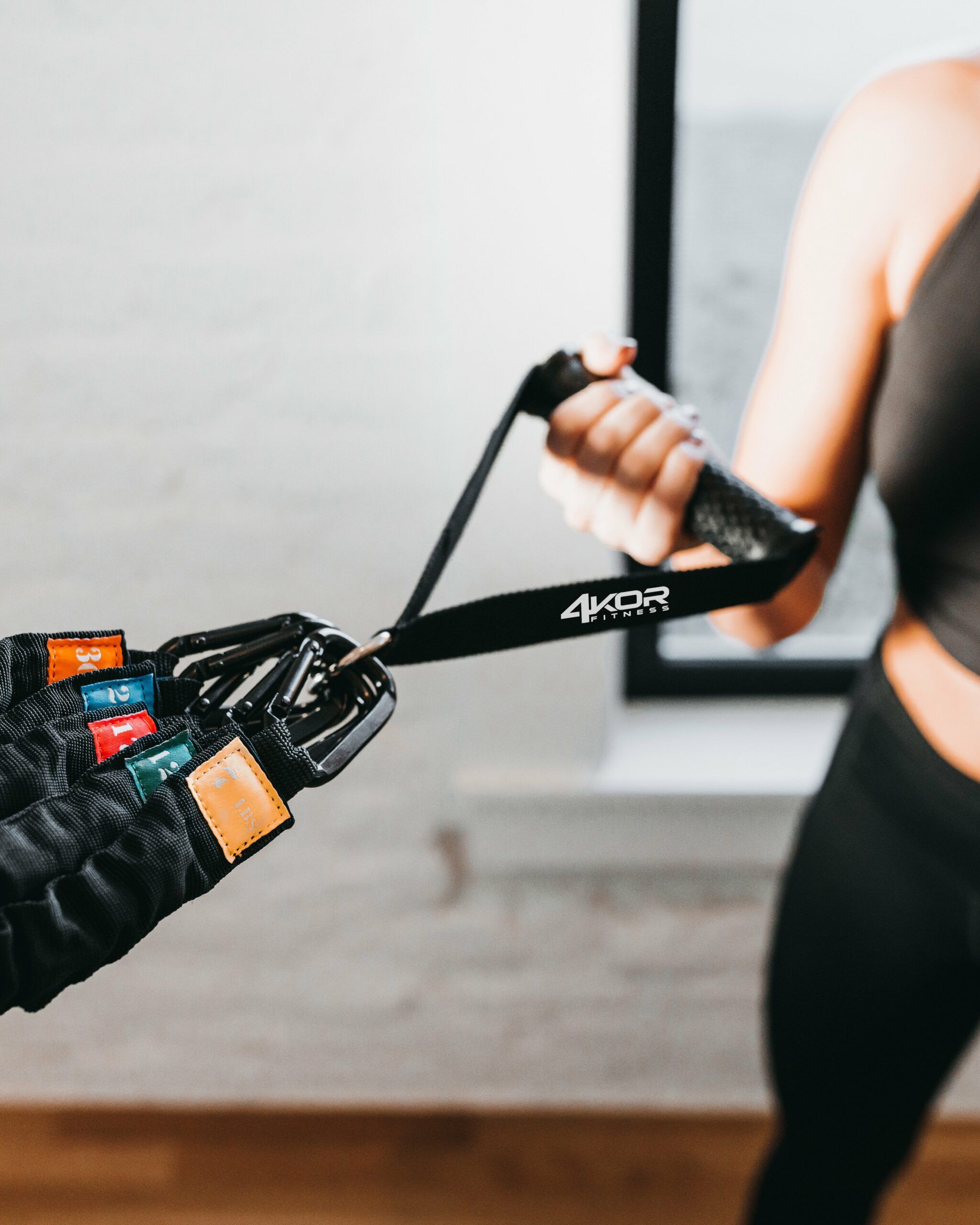 Female athlete holding 4KOR Fitness exercise handle connected to multiple color-coded resistance cords for the Deluxe Resistance Cord System